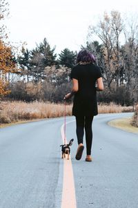 Rear view of man with dog on road