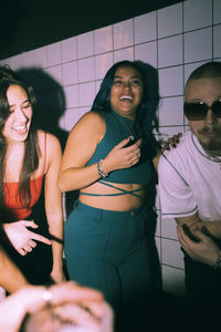 Cheerful young women and man dancing together at nightclub