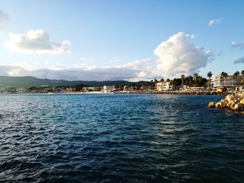 Sea by buildings against sky in city