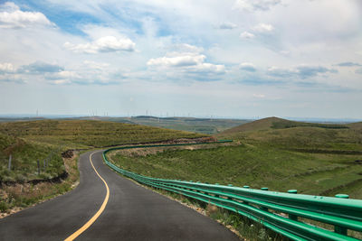 Under the blue sky and white clouds, a flat broad asphalt road leads to the front