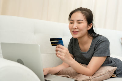 Young man using mobile phone while sitting on sofa