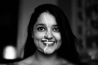 Portrait of smiling young woman with face paint looking away sitting at home