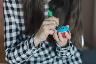 Midsection of girl drawing on easter egg