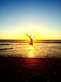 Silhouette man on beach against sky during sunset