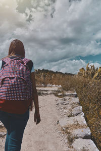 Rear view of man walking on mountain against sky