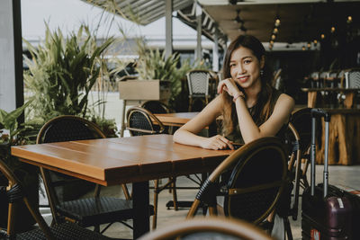 Portrait of woman sitting on chair at restaurant