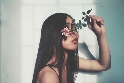 Close-up of young woman holding flowering plant