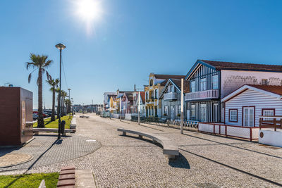 Street amidst buildings against clear sky on sunny day