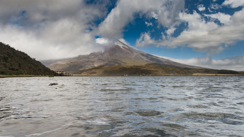 Scenic view of lake and mountains against cloudy sky