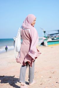 Woman wearing hijab walking at beach on sunny day