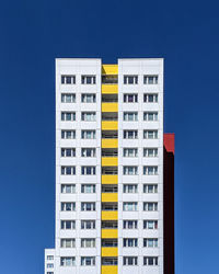 Low angle view of apartment building against clear blue sky