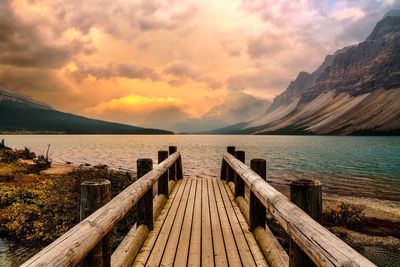 Wooden pier over lake against sky during sunset