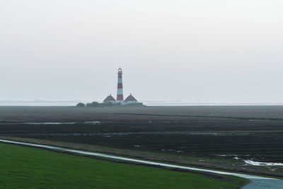 Lighthouse by sea against clear sky