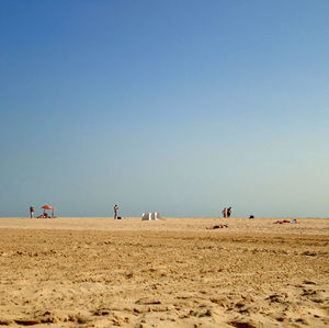 People at beach against clear sky