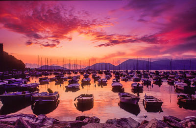 Boats moored at harbor during sunset