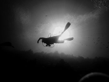 Low angle view of silhouette helicopter in sea against sky