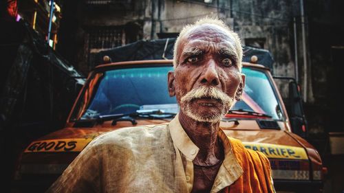 Portrait of senior man standing against truck in city