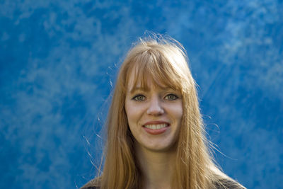 Portrait of smiling young woman against blue sky