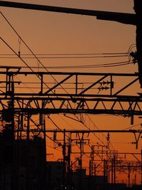 Low angle view of silhouette electricity pylon against sky during sunset