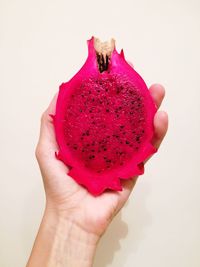 Close-up of hand holding strawberry over white background