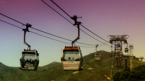 Cable cars over mountains against clear sky during sunset