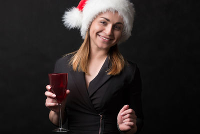 Portrait of a smiling young woman against black background