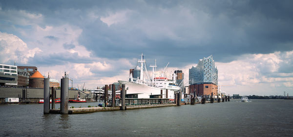 Hamburg, elbe philharmonic hall from the water with  view of harbor and hafencity under cloudy sky