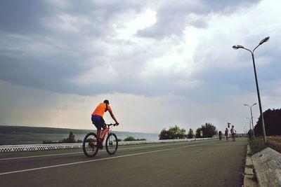 Man riding bicycle on road against sky