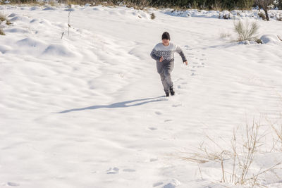 Child running in the snow on a sunny day,