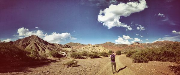 Rear view of woman walking on desert against sky