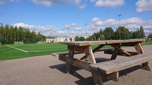 Empty chairs and table in park against sky