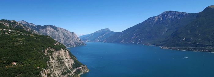 Scenic view of lake garda and mountains against clear blue sky