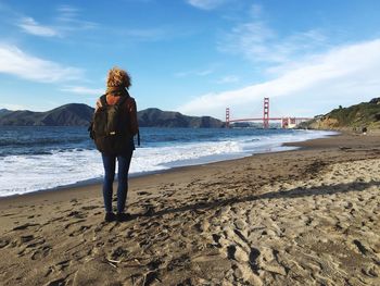 Rear view of woman standing on shore at marshall beach