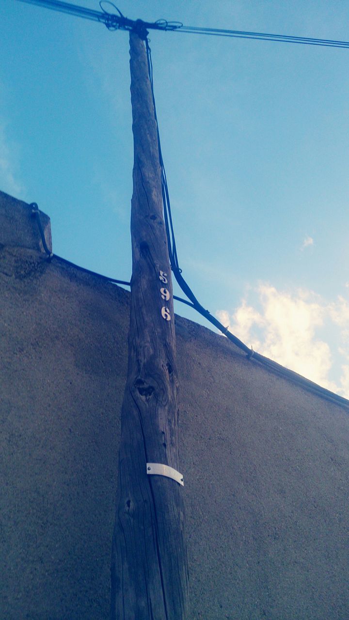 low angle view, sky, built structure, architecture, blue, building exterior, day, sunlight, outdoors, no people, old, cloud, fuel and power generation, clear sky, part of, shadow, nature, connection, wood - material, weathered