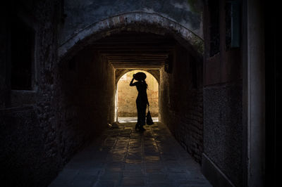 Silhouette woman standing in arch pathway