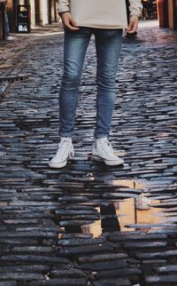 Low section of man standing by puddle on street