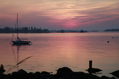 Silhouette sailboat sailing in river at sunset