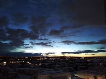 Illuminated buildings in city against sky at dusk