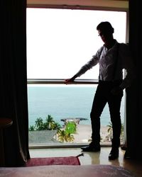 Man standing by window against clear sky
