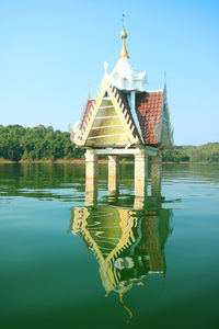 Reflection of building in lake against clear blue sky