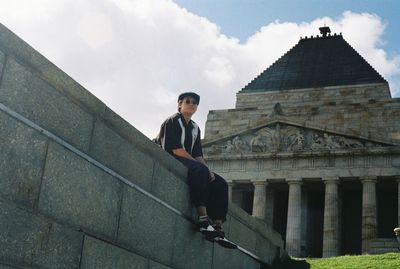 Full length portrait of young man standing against building