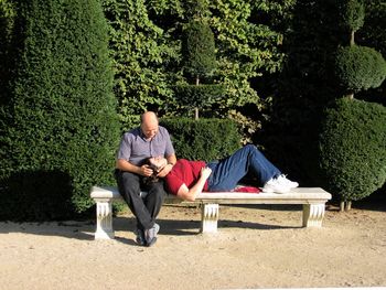 Full length of men sitting on grassland against trees