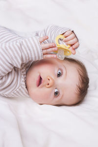 Baby girl with dummy lies down on a white blanket