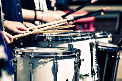 Midsection of people playing drum at music concert