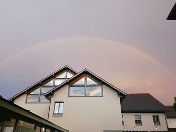 Low angle view of rainbow over building against sky