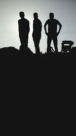 Low angle view of silhouette men standing against sky