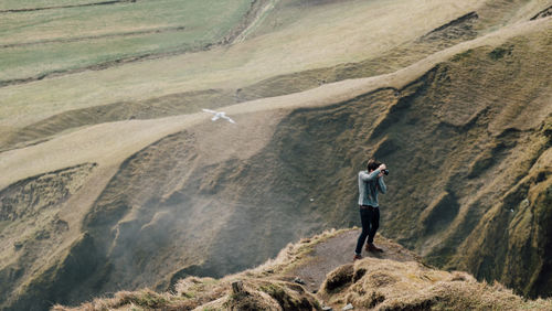 Rear view of man photographing on mountain