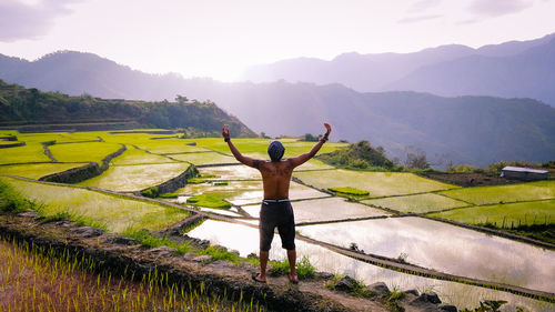 Rear view of man standing on mountain against sky