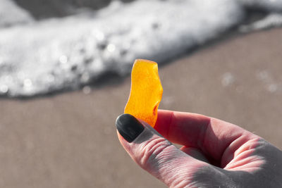 Beautiful big piece of yellow amber in the hand of a girl with water and sea waves on the background