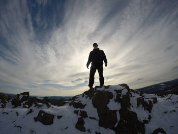Silhouette man standing on snow covered mountain